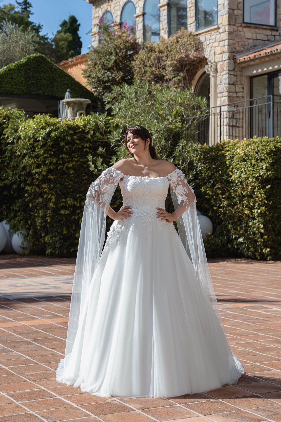 La robe de mariée grande taille  fluide trapèze  en dentelle décolleté bateau avec manches en tulle évasées modèle Clara qui reflète votre élégance chez solution cérémonie à Marseille